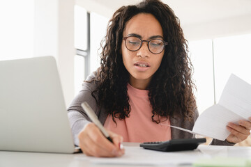 Young african freelancer businesswoman student counting paying domestic bills, debts, e-banking...