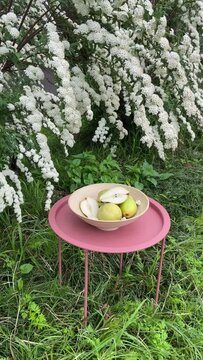 Ripe pears in a wooden basket on a metal garden table