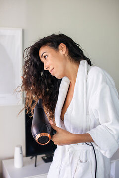 Pleased woman drying hair in morning. Woman in bathrobe getting ready for new day. Home, morning routine concept