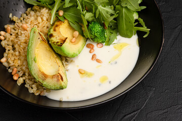 bulgur with avocado, hot dish with avocado and bulgur on a black background side view