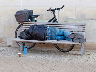 homeless person, Adult Man sleeping on a bench in a park at day in the city. 