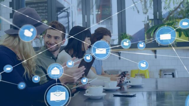 Animation Of Network Of Digital Icons Over Diverse Businesspeople Using Electronic Devices At Office