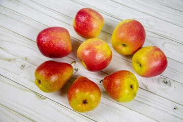 Bright pink apples and pears arranged in a circle on a gray wooden table. Vegetables and fruits. Useful products.