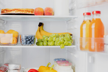 Front View of open two door fridge or refrigerator door filled with fresh fruits, vegetables,...