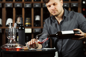 Sommelier pouring red wine from bottle in glass