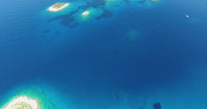 Reefs, underwater meadows, small islands, rocky sea bottom, tourist boats and crystal clear Aegean Sea with magnificent sun reflections are in high altitude aerial shoot.