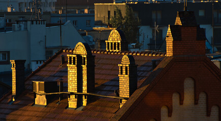 chimneys on the roof of the building glistening in the sun during the golden hour