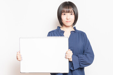 大きいスケッチブックを持っている若い女性