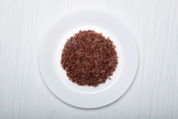 Asian food cooked red rice in plate isolated on white wood background.
