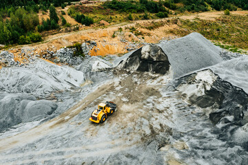 Aerial view of Truck excavator in open sand quarry rubble in Finland.