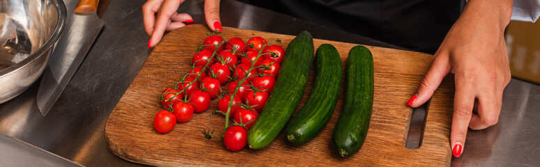 cropped view of african american woman near ripe vegetables on cutting board, banner.