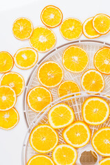 on a white round grate, sliced orange for further drying