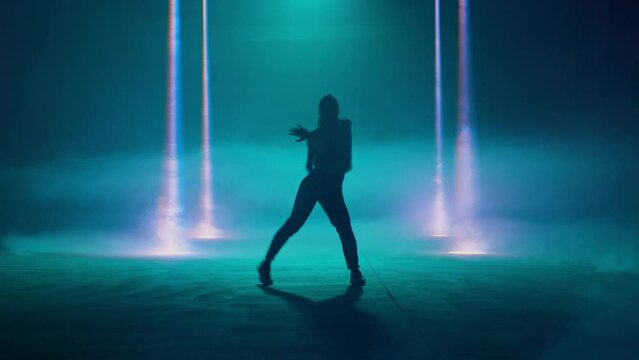 Female dancer performing in the night club. Contemporary dance. Silhouette in a blue neon lights