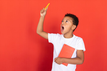 Portrait of excited preteen boy holding book and pen. Mixed race child wearing white T-shirt...