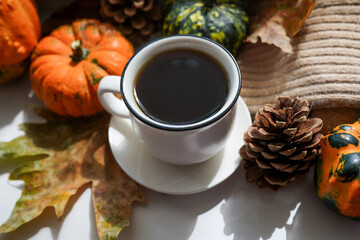 Autumn, fall leaves, hot steaming cup of coffee and a warm scarf on white table background. Seasonal, morning coffee, Sunday relaxing and still life concept