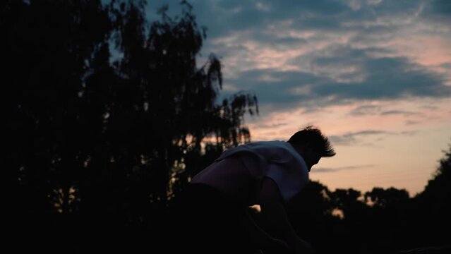 A cool jump from a coup against the background of the sunset sky was performed by a guy. Cool sports entertainment