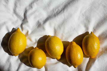 fresh yellow lemons in sunlight  on bed on bed. hard light - obrazy, fototapety, plakaty