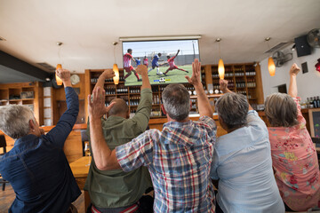 Diverse senior friends in bar watching tv with football match on screen - Powered by Adobe
