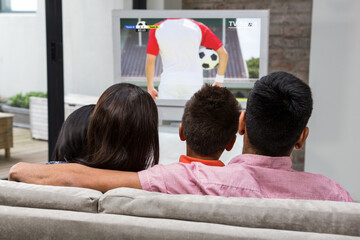 Caucasian family watching tv with football match on screen