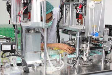 Asian worker inspecting quality of mask and medical face mask production line, Industry and factory concept.