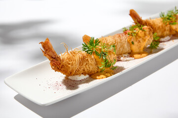 Traditional greek appetizer - kataifi wrapped shrimps on white plate. Crispy shrimp in kataifi...