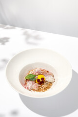 Creative creamy risotto with eel and cheese espuma. Fish risotto on white plate with unagi sauce and eel in summer menu Italian risotto from chef with smoked eel and spinach with shadows of leaves