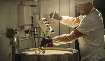 Man is a cheese maker in the process of producing different varieties of cheese in the industry. Milk cheese making