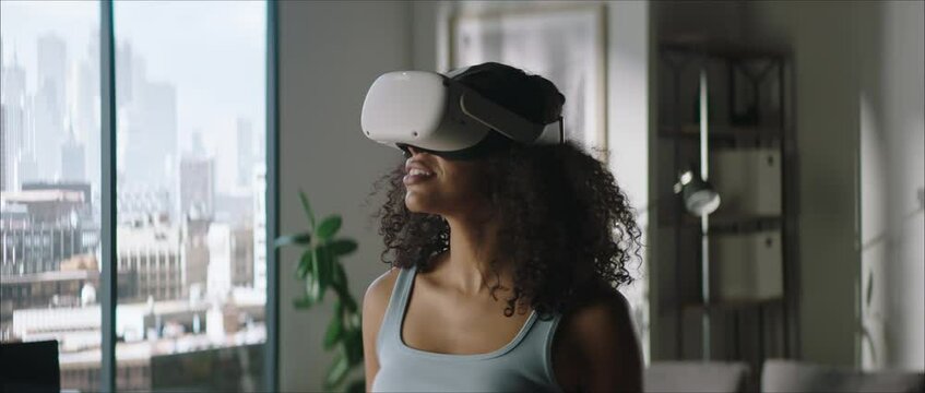 Portrait of excited African American female using her VR virtual reality metaverse headset at home