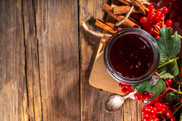 Autumn jam recipe, conservation and harvest season. Homemade red jam from organic viburnum berries, with fresh berries on twigs and cinnamon