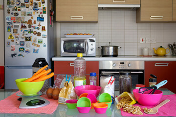 Home kitchen table with all the ingredients, cupcake holders and other things needed for carrot cupcakes preparation   