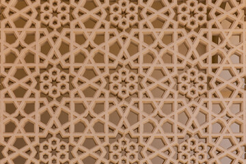 Arabic style carved stone openwork on a building facade in Old Dubai (Deira), with star and floral geometric shapes and patterns.