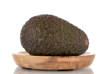 One ripe organic avocado on a wooden saucer, close-up, isolated on a white background.