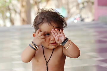 Adorable Little child covering his one eye with his hands and without clothes
