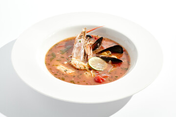 Tomato seafood soup in plate isolated on white background. Seafood stew Cioppino - shrimp,  mussels and salmon in tomato broth. Seafood dish in Italian restaurant menu.