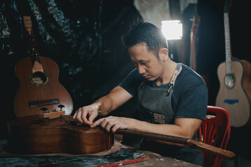 Guitar makers asian man making acoustic guitars in laboratory. Asian guitar maker builds high...