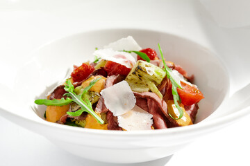 Roast beef and grilled vegetables salad isolated on white background. Steak salad with pastrami, eggplant, tomato, remoulade sauce with parmesan flakes. Gourmet dish  with grilled meat and vegetables.