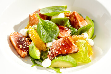 Healthy lunch - green salad with tuna, avocado and orange. Tuna salad for diet. Clean eating in restaurant menu. Grilled Fish with spinach, avocado, citrus isolated on white background. Keto diet.