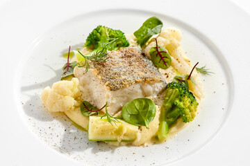 Roasted cod with mashed potatoes and broccoli. White fish fillet with skin with vegetables isolated on white background. Healthy food in restaurant menu. Fish and cabbages in minimalism style.