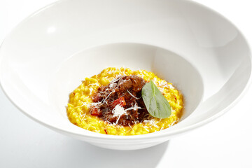 Risotto alla milanese with meat ragu. Saffron risotto with lamb meat isolated on white background. Yellow risotto in white plate. Italian classic cuisine in restaurant menu.