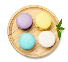 Round macaroons with different flavors on a wooden plate, top view.