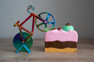 colorful knife cutter in shape bicycle on bright birthday piece of sponge cake, cut a cake,...