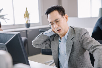 A businessman who works in the office looks tired and stressed by pressing her hands