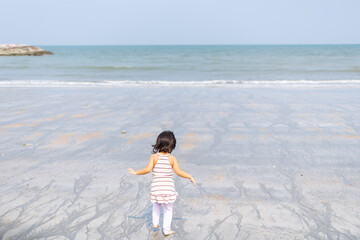 A girl having fun running on the beach by the sea in the daytime, the children's vacation in the summer.
