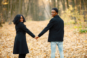 Loving black couple walking in park and enjoying autumn day