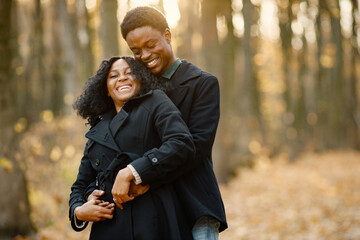 Fototapeta premium Loving black couple walking in park and enjoying autumn sunset