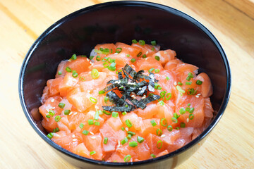 Diced raw salmon with Japanese rice in black bowl. Donburi menu.