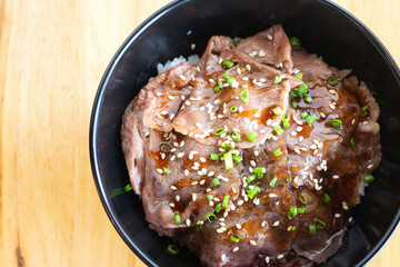 Wagyu beef Donburi with Japanese rice in black bowl.