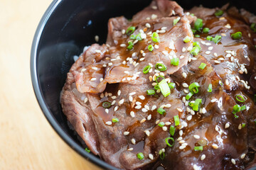 Wagyu beef Donburi with Japanese rice in black bowl.