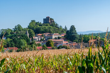 Château de busséol en haut de son promontoire avec le village a ses pieds et un beau champs de...