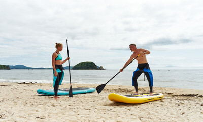 A man SUP board instructor on the shore teaches a girl how to stay on the water. Active rest on the...